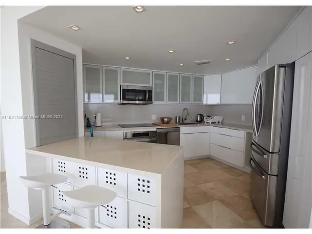 a kitchen with granite countertop a refrigerator stove top oven and sink