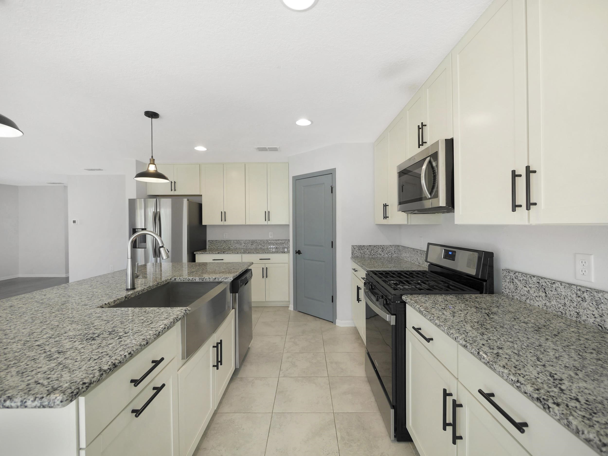 597 Meadow Ridge Drive St. Augustine, FL 32092 - Photo 16 of 56 a kitchen with granite countertop a sink and a stove