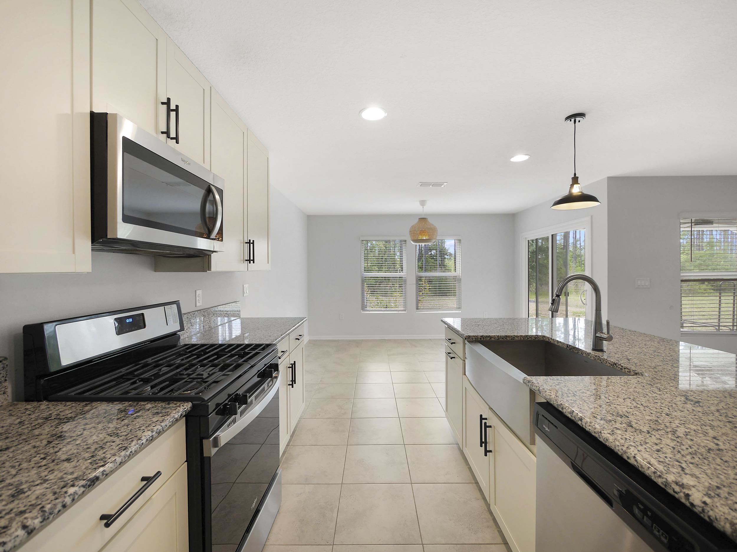 597 Meadow Ridge Drive St. Augustine, FL 32092 - Photo 17 of 56 a kitchen with granite countertop a sink and stove top oven