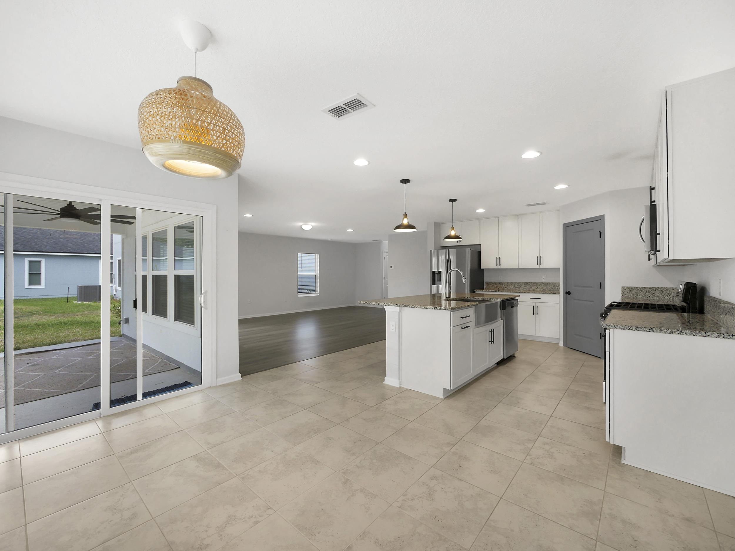 597 Meadow Ridge Drive St. Augustine, FL 32092 - Photo 21 of 56 a large kitchen with stainless steel appliances kitchen island granite countertop a large counter top and a stove