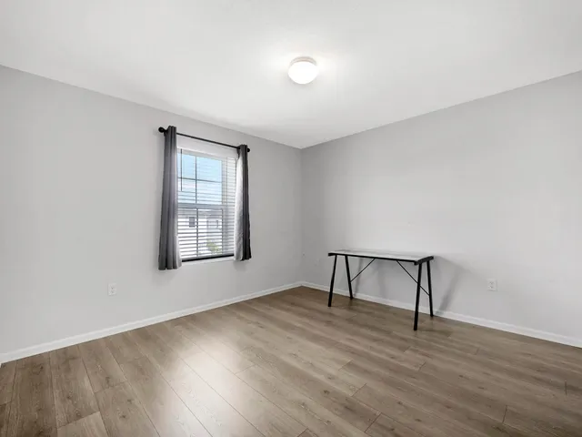 an empty room with wooden floor and window
