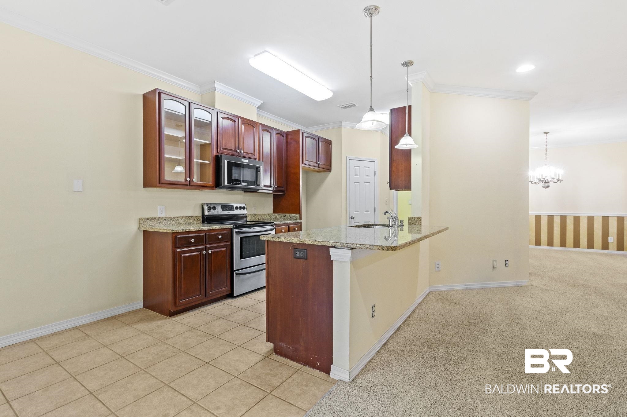 166 Club Drive Fairhope, AL 36532 - Photo 11 of 41 Kitchen featuring crown molding, light stone counters, kitchen peninsula, hanging light fixtures, and appliances with stainless steel finishes
