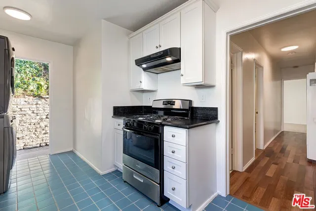 a kitchen with granite countertop white cabinets and stainless steel appliances