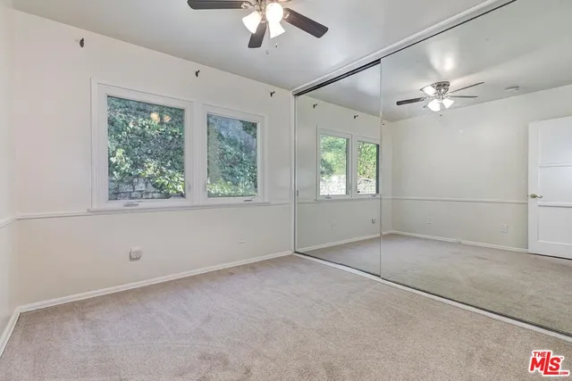 an empty room with a chandelier fan and windows