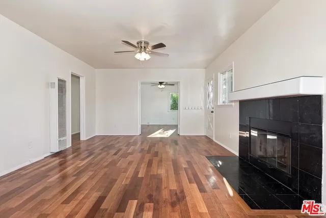 a view of empty room with wooden floor and fan