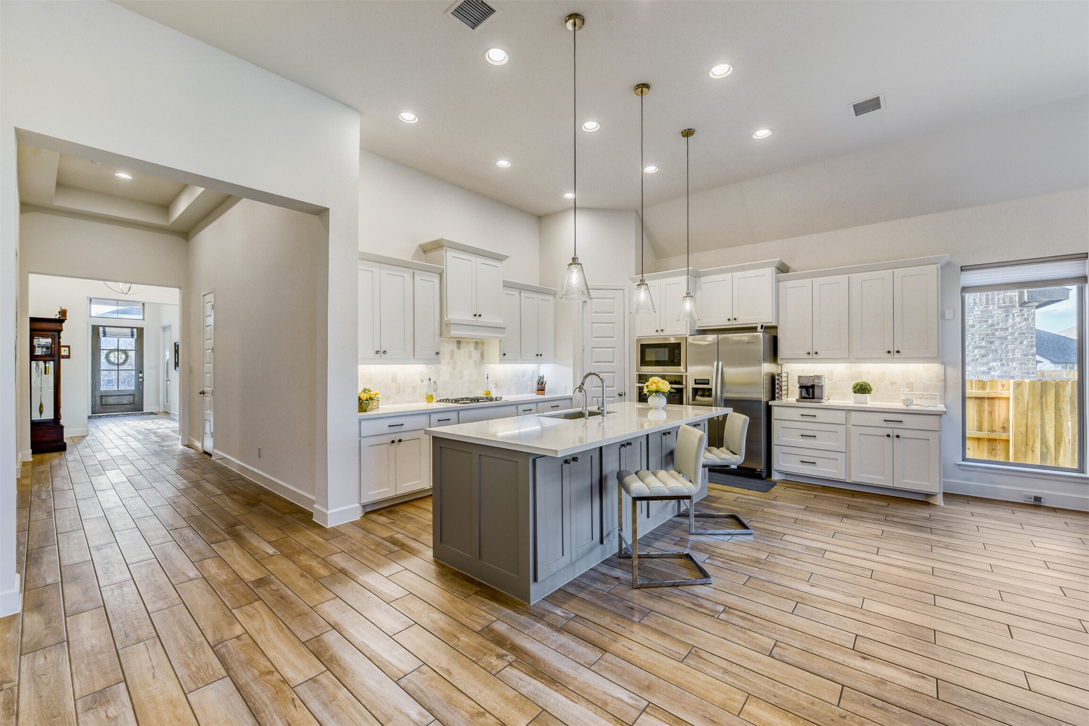 345 Prickly Poppy Loop Kyle, TX 78640 - Photo 11 of 28 Two tone kitchen featuring healthy amount of natural light, decorative backsplash, a breakfast bar, two tone color scheme, and a high ceiling
