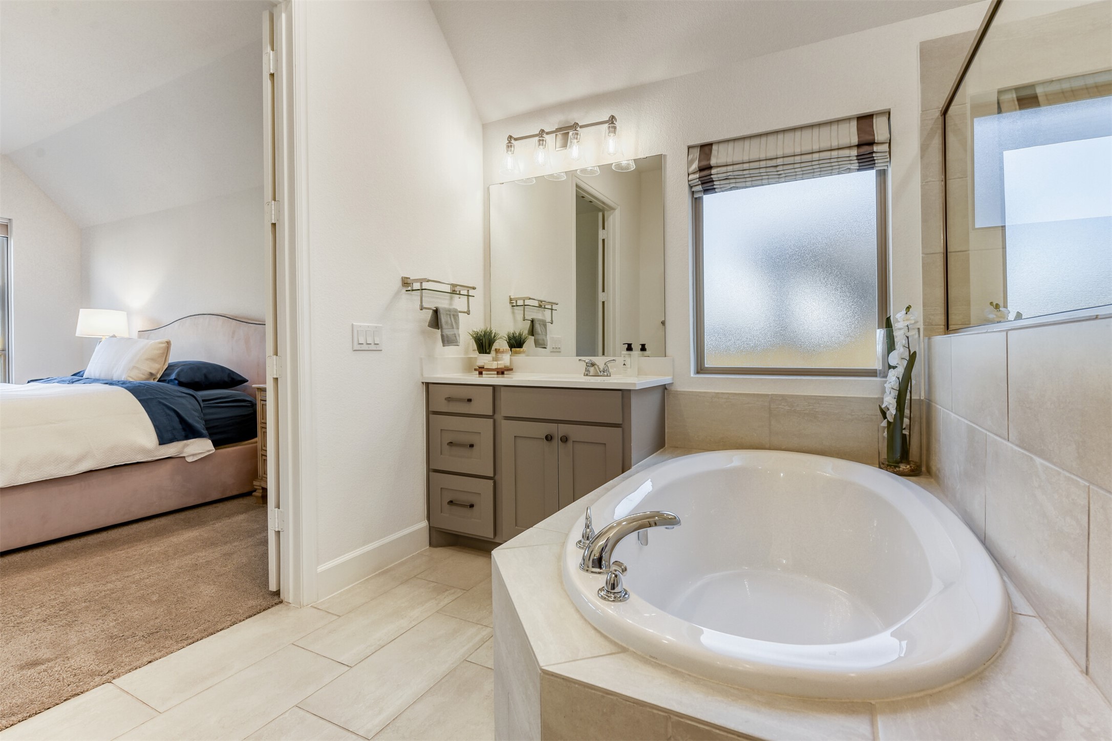 345 Prickly Poppy Loop Kyle, TX 78640 - Photo 14 of 28 Ensuite bathroom with a bath, vanity, vaulted ceiling, light colored carpet, and light tile patterned floors