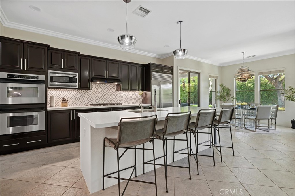79690 Rancho San Pascual La Quinta, CA 92253 - Photo 11 of 73 a kitchen with stainless steel appliances granite countertop a stove top oven a sink a dining table and chairs with wooden floor