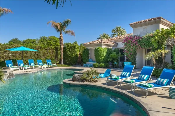 a view of a swimming pool with a table and chairs under an umbrella
