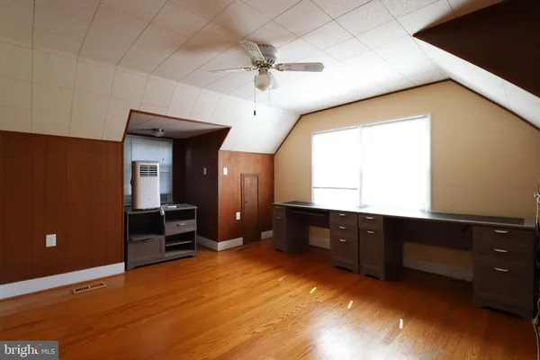 an empty room with wooden floor and fan