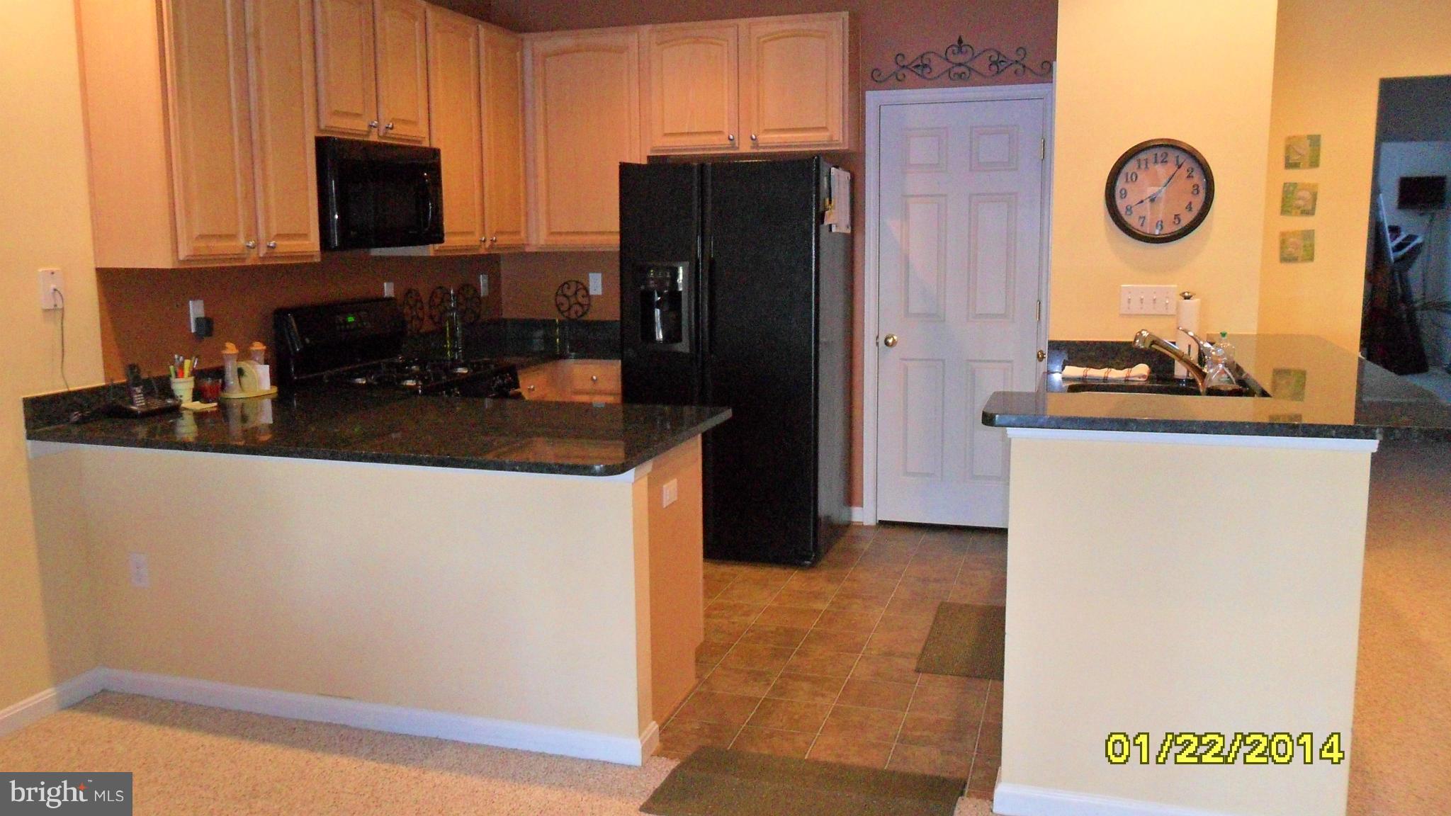 14232 Foxhall Road, Unit 17 Dowell, MD 20629 - Photo 7 of 11 a kitchen with a refrigerator and a stove top oven