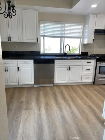 a kitchen with granite countertop white cabinets white appliances and a window
