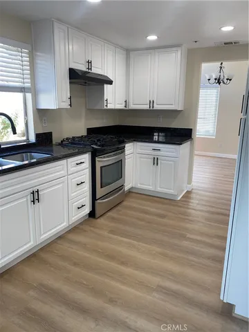 a kitchen with granite countertop white cabinets and black appliances