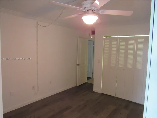 an empty room with wooden floor fan and window