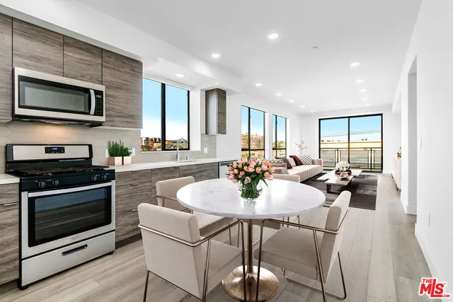 a kitchen with a dining table chairs and stainless steel appliances