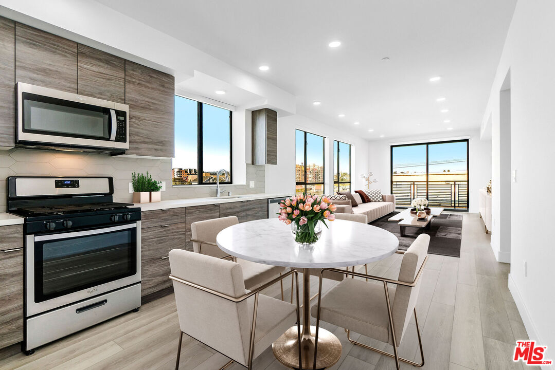 3632 Keystone Avenue, Unit 302 Los Angeles, CA 90034 - Photo 3 of 38 a kitchen with a dining table chairs and stainless steel appliances