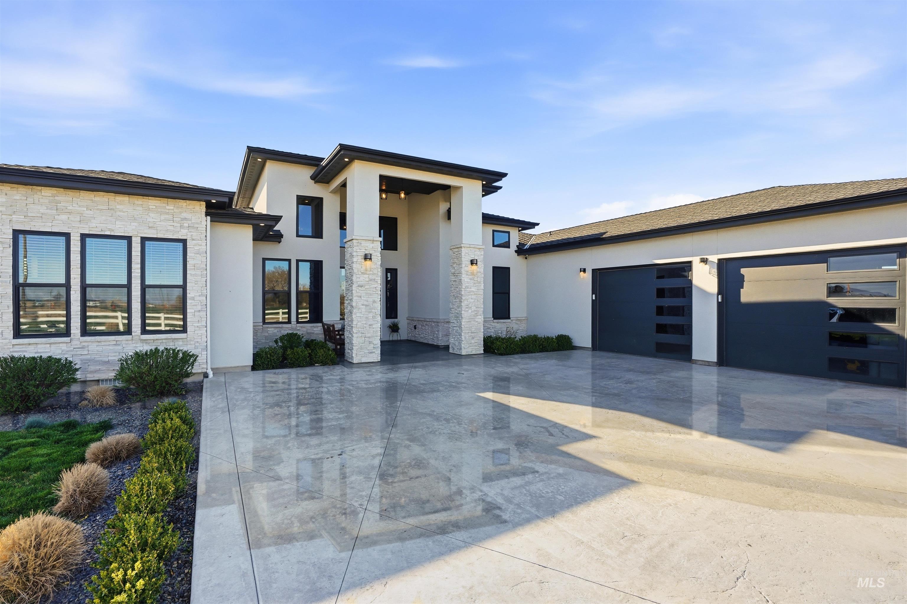 Contemporary home with stone siding, driveway, stucco siding, and an attached garage