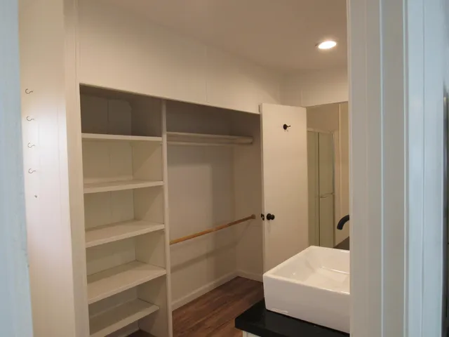a view of a hallway with wooden floor and a ceiling fan