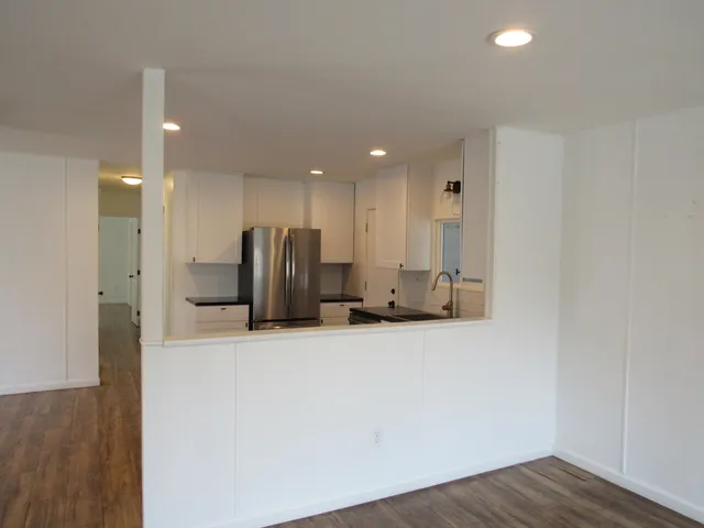 a view of an empty room with wooden floor and a window