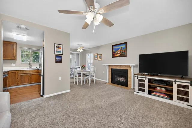 a view of a livingroom with furniture a fireplace a flat screen tv and a ceiling fan