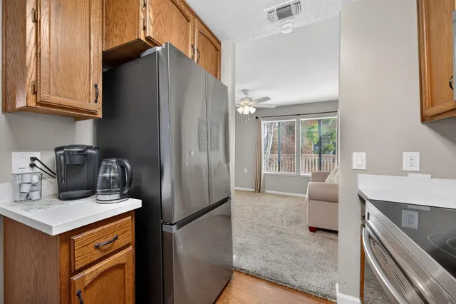 a kitchen with stainless steel appliances granite countertop a refrigerator a stove and a sink with wooden cabinets