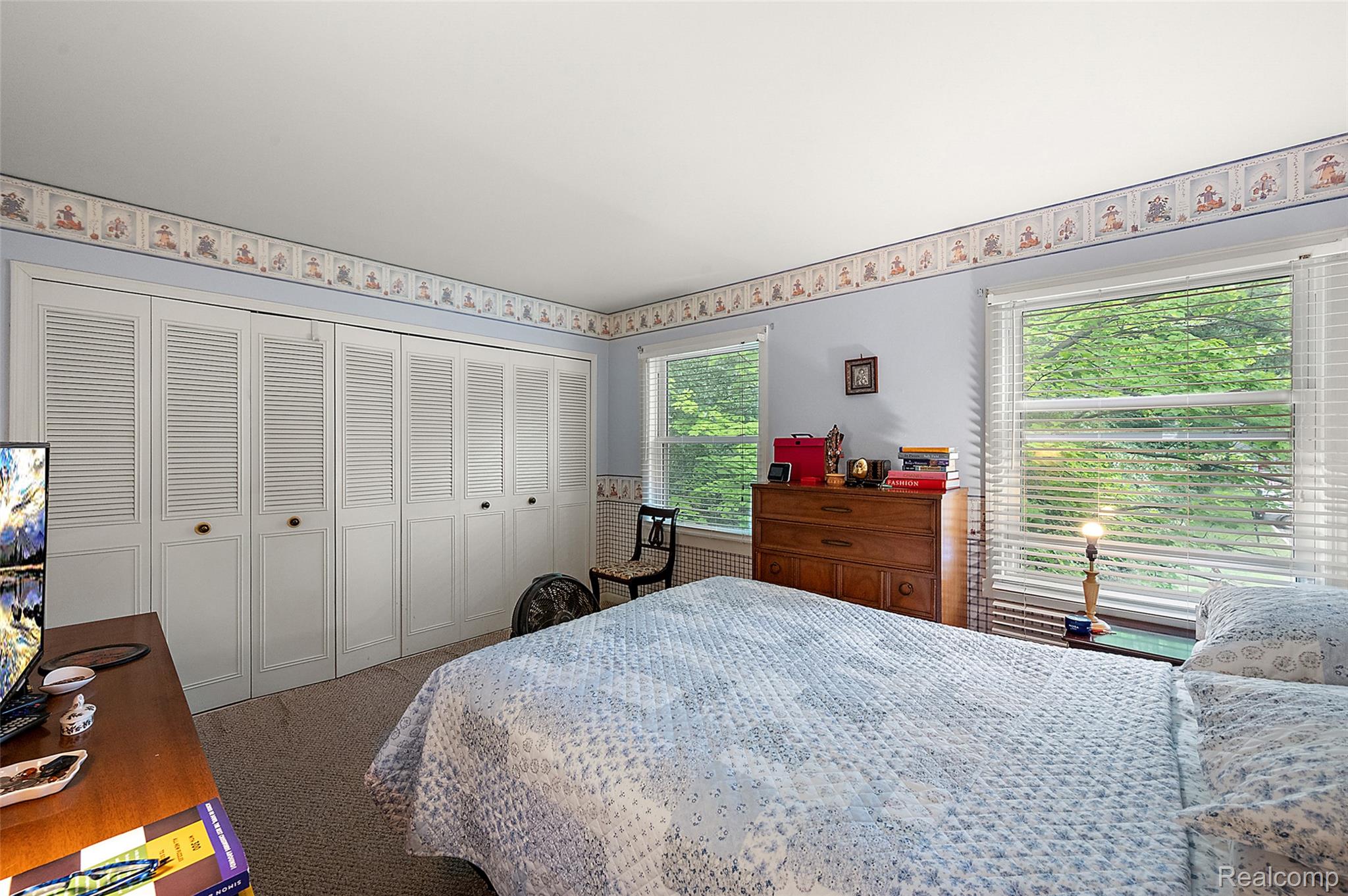 930 Little Hill Court Rochester, MI 48307 - Photo 30 of 38 Bedroom featuring a full-wall built-in louvered bi-fold closet system, dual windows with horizontal blinds, and a neutral carpet