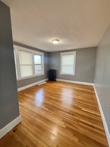 a view of an empty room with window and wooden floor