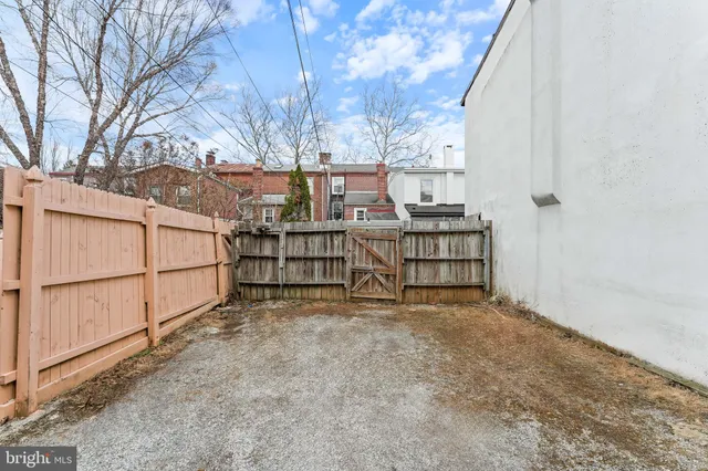 a view of backyard with wooden fence and large trees