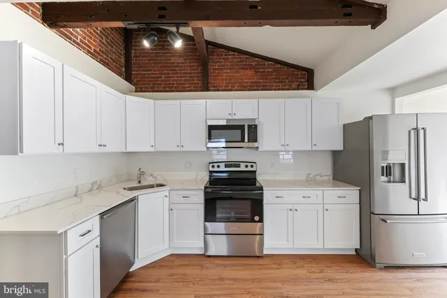 a kitchen with a sink stainless steel appliances and white cabinets