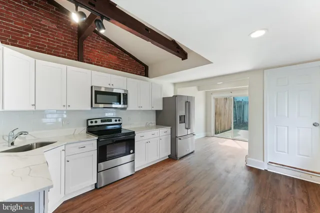 a kitchen with stainless steel appliances granite countertop a refrigerator a sink dishwasher a stove and white cabinets with wooden floor