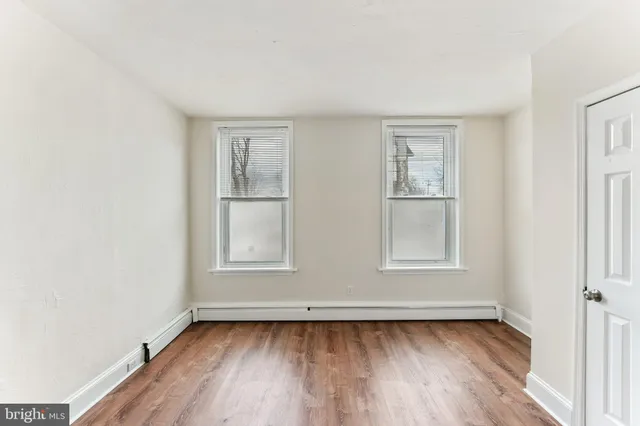 an empty room with wooden floor and window