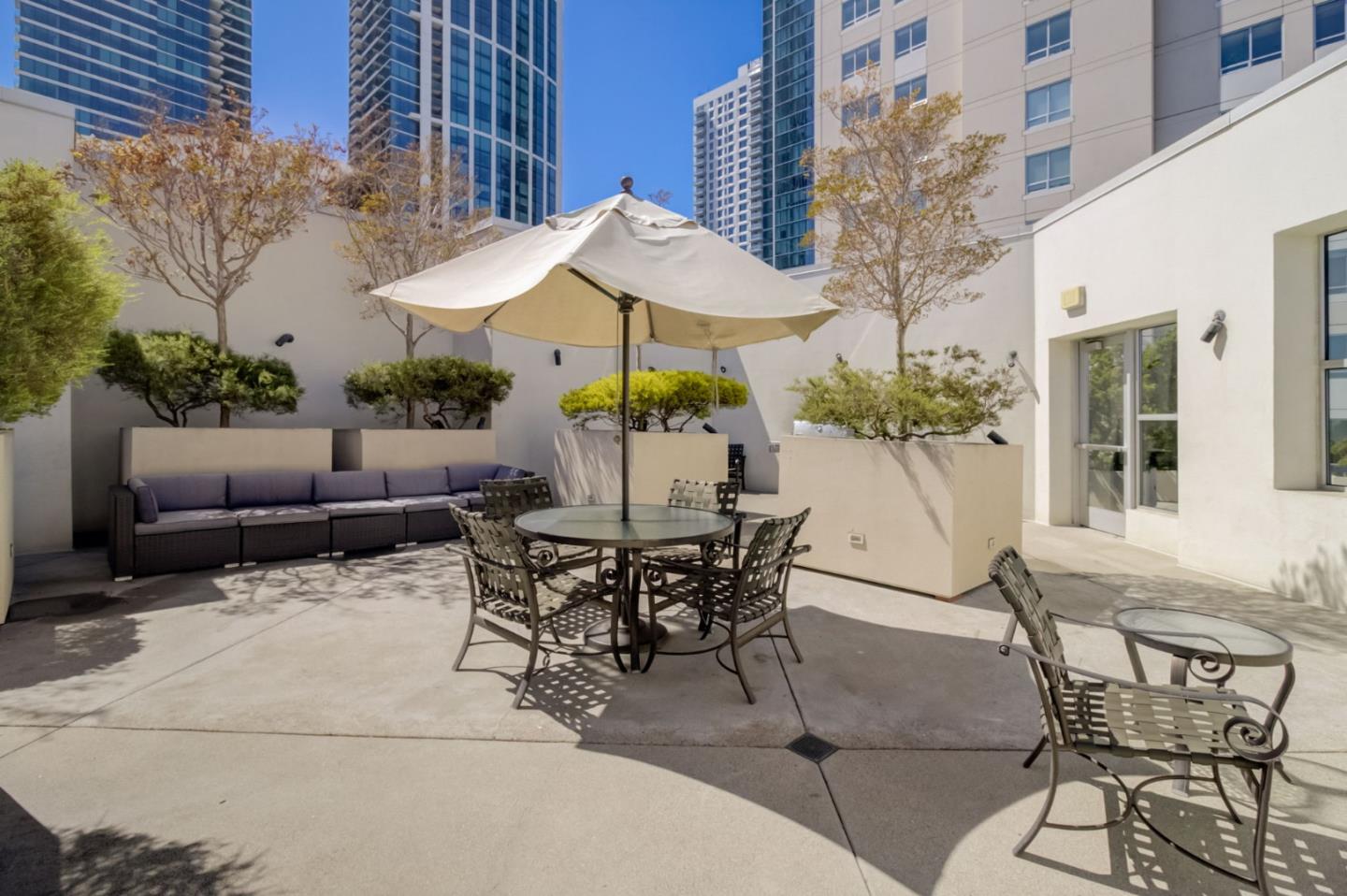 400 Beale Street, Unit 612 San Francisco, CA 94105 - Photo 30 of 38 a view of a patio with couches table and chairs under an umbrella with a fire pit
