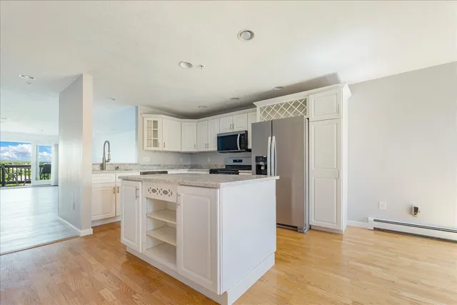 a kitchen with stainless steel appliances granite countertop a stove top oven a sink a refrigerator and white cabinets