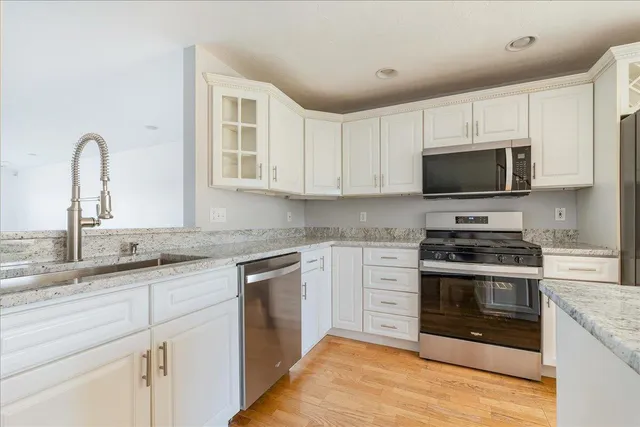 a kitchen with stainless steel appliances granite countertop a stove top oven a sink and dishwasher with wooden floor