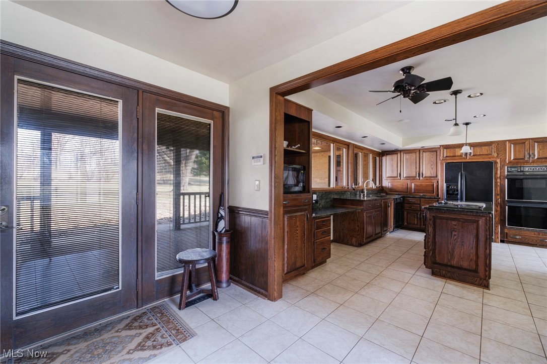 7059 Stewart Sharon Road Hubbard, OH 44425 - Photo 22 of 49 Kitchen featuring black appliances, a ceiling fan, a kitchen island, dark countertops, and light tile patterned floors