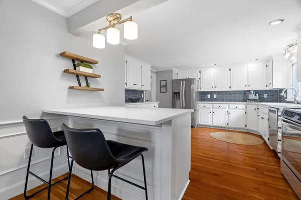 a kitchen with kitchen island granite countertop a stove a sink a chandelier and a refrigerator