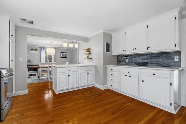 a kitchen with stainless steel appliances white cabinets and wooden floors