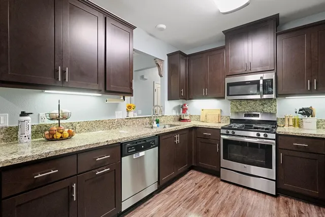 a kitchen with granite countertop stainless steel appliances and wooden cabinets