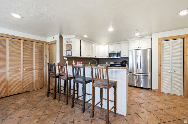 335 Bern Way Midway, UT 84049 - Photo 64 of 88 Kitchen featuring white cabinetry, stainless steel appliances, a light-toned countertop, and an island with seating