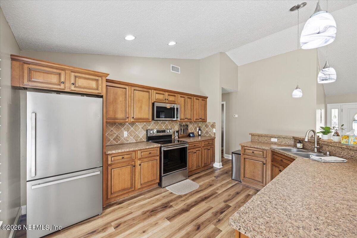 54130 Church Road Callahan, FL 32011 - Photo 12 of 42 a kitchen with stainless steel appliances granite countertop a refrigerator a stove a sink dishwasher and a refrigerator with wooden floor
