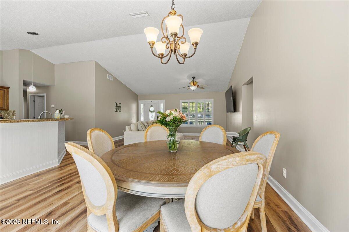 54130 Church Road Callahan, FL 32011 - Photo 19 of 42 a dining room with wooden floor a chandelier a wooden table and chairs