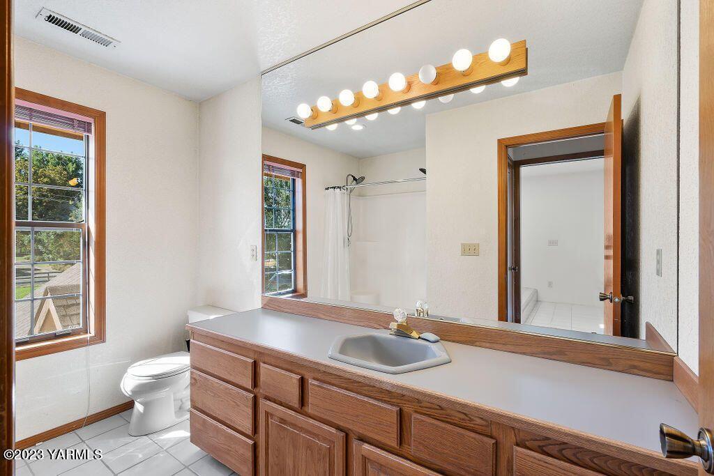 1703 Stein Road Yakima, WA 98908 - Photo 28 of 41 a bathroom with a granite countertop sink a toilet and mirror