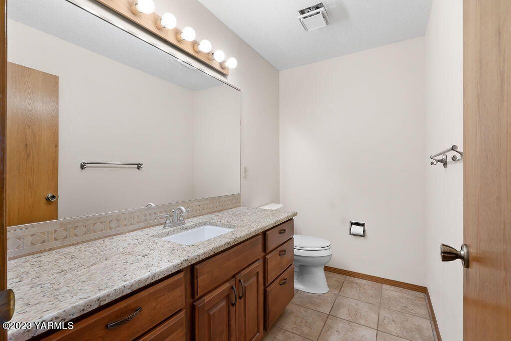 1703 Stein Road Yakima, WA 98908 - Photo 30 of 41 a bathroom with a granite countertop sink a toilet and a mirror
