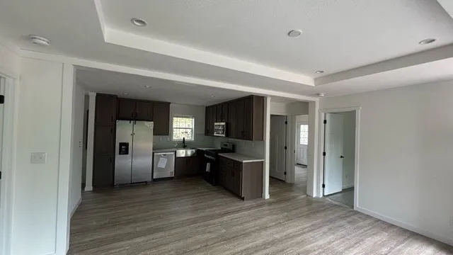 a view of a kitchen with a sink refrigerator and wooden floor