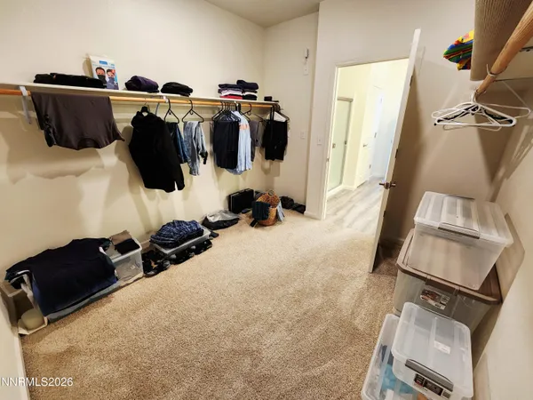 a walk in closet with clothes and shoes