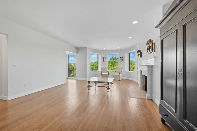 a view of a livingroom with furniture a fireplace wooden floor and a window