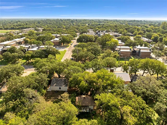 an aerial view of residential houses with city and green space