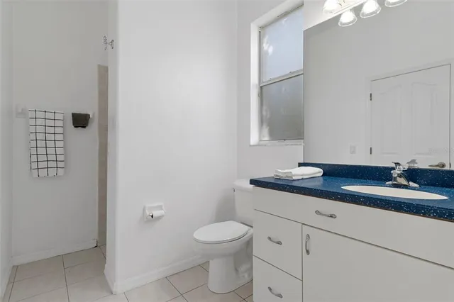 a bathroom with a granite countertop toilet a sink and a mirror