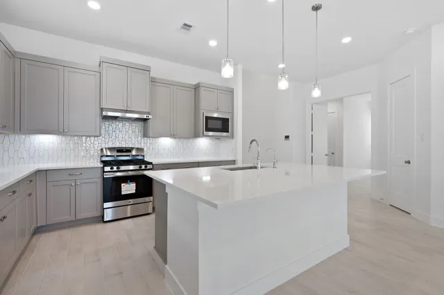 a large white kitchen with a stove and a sink