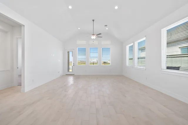 an empty room with windows and chandelier fan